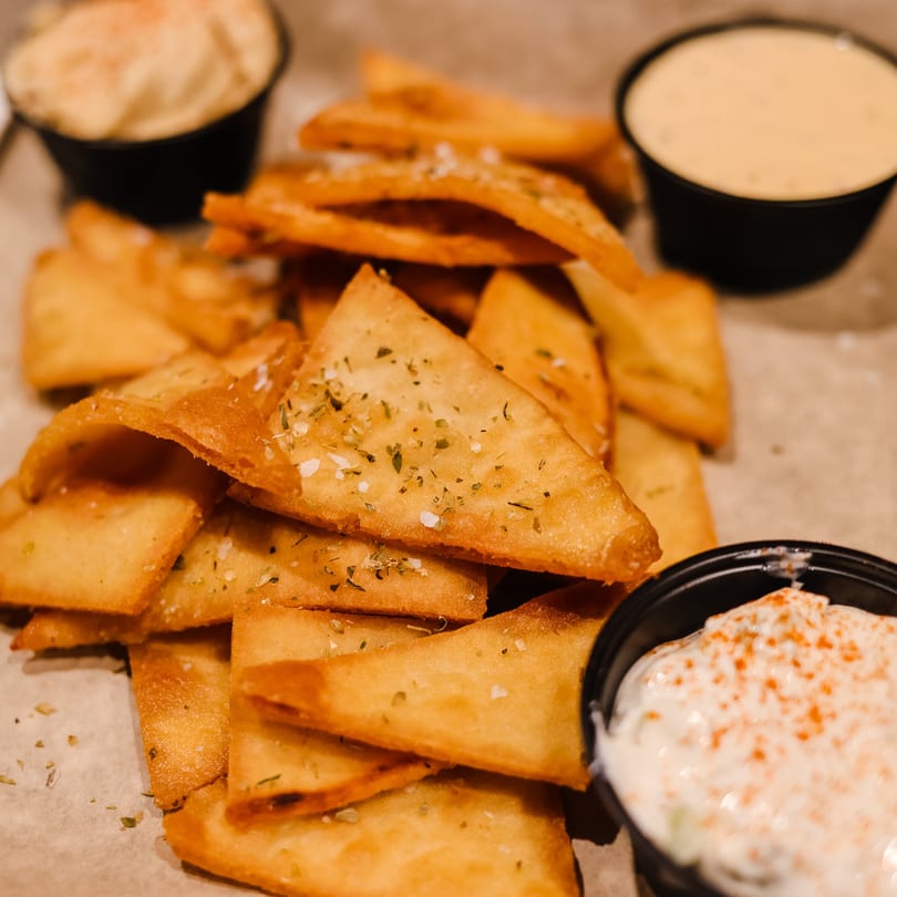 Crispy pita chips seasoned with herbs and salt, served with two dipping sauces at Spyro's Gyros.